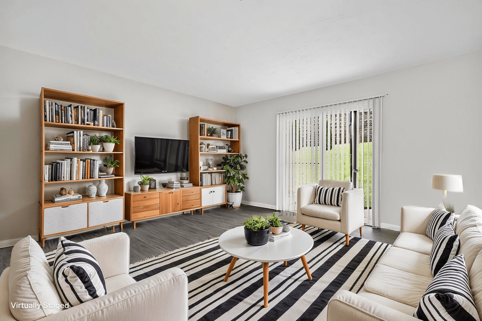 A living room with a white couch, a coffee table, and a television.